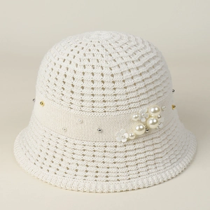Detail of white hollow knit sun hat with elegant pearl accents and 3D floral ornaments