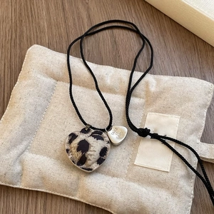 Close-up of leopard print heart pendant with Take It Easy tag on black braided cord