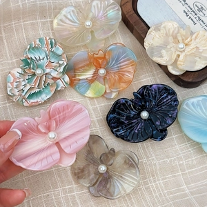 Elegant acetate orchid hair clips with pearl centers in assorted colors on linen
