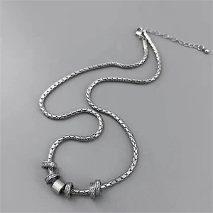 Detail of silver titanium steel necklace with five sparkling zircon paved rings
