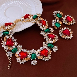 Macro detail of vintage gold jewelry set with red heart gems and green stones