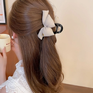 Detail of cream bow claw clip on hair showing elegant aesthetic and secure hold design