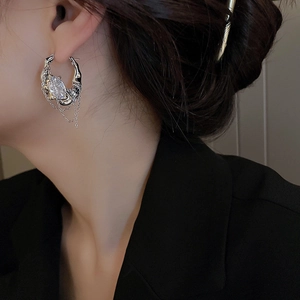 Detailed close-up of silver tassel earrings with crystals on a model in black suit