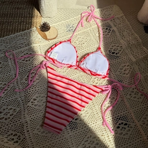 Dettaglio bikini a righe rosa e rosse con etichetta taglia S e materiale in primo piano