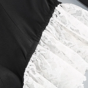 Detailed view of sexy V-neck bodysuit with black fabric and white lace trim stitching