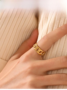 Detailed macro view of an 18K gold plated Cuban link chain ring on a finger