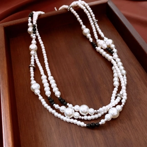 Détail du collier de perles multicouche avec perles argentées serties sur plateau bois