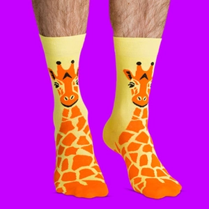 Detail shot of yellow cotton socks with giraffe pattern on model legs against purple background