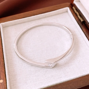 Macro detail of silver-tone metal cuff bracelet with cubic zirconia on a wooden jewelry box
