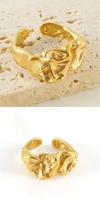 Detail of 18K gold stainless steel open ring with irregular lava texture on travertine