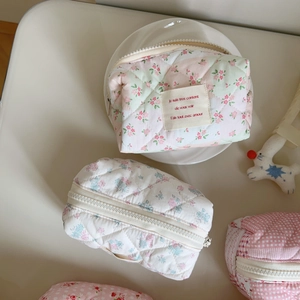 Detailed close-up of floral quilted cosmetic bag with zipper and decorative fabric label