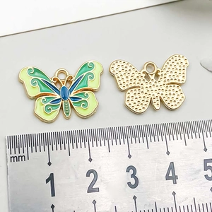 Macro detail of gradient butterfly charms with dimensions measured by a ruler