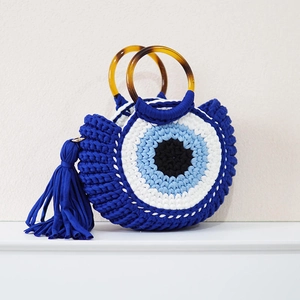 Detailed view of evil eye knit bag with tortoiseshell handles and tassel charms