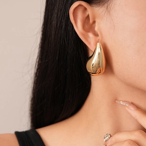 Polished golden teardrop earrings on model showcasing elegant high-shine metallic finish
