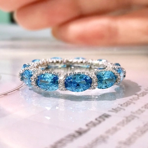 Macro shot of a silver ring featuring an oval blue gemstone and micro-pave crystals