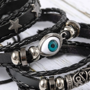 Macro detail of multi-layer leather bracelets with blue evil eye and star metal charms