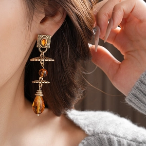 Detail of vintage geometric earrings with amber beads and bronze teardrop pendants