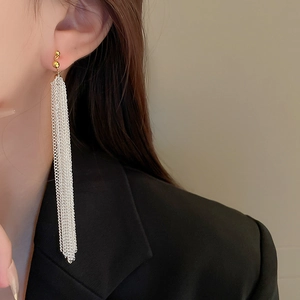 Detail of long gold ball studs with silver chain tassels worn with a black suit jacket