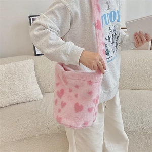 Close-up of pink plush underarm bucket bag with heart patterns worn by a model