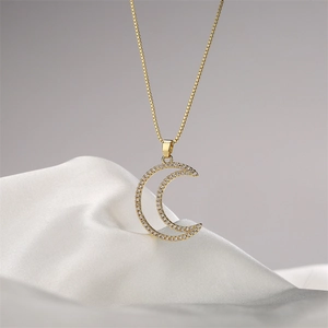 Collana con ciondolo a luna dorata e micro-pave di zirconi su sfondo di seta bianca