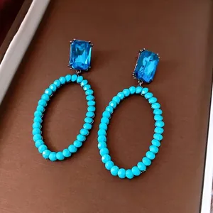 Vintage oval hollow earrings with bright blue crystals and silver needles in retro design