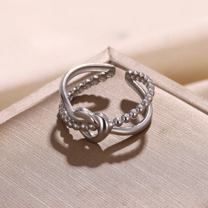 Detail of silver double-layered open ring featuring a stylish knot and beaded band texture