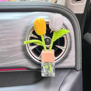 Handmade knitted tulips in glass jar car aromatherapy diffuser on dashboard air vent