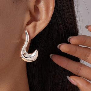Close-up of polished silver irregular geometric earrings worn by a model in detail