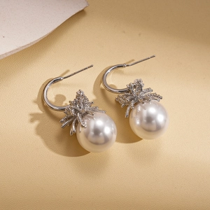 Elegant C-shaped pearl earrings with silver firework-style base on a minimalist background