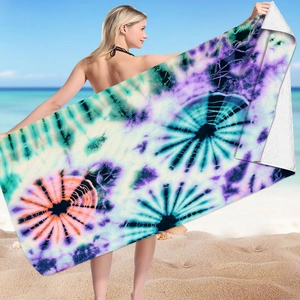 Detailed view of colorful tie-dye microfiber beach towel held against a sunny ocean backdrop