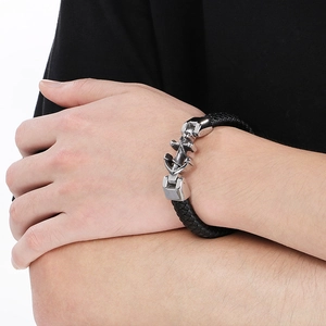 Detail of black braided leather bracelet with silver metal anchor clasp on a wrist