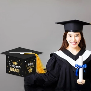 Close-up of black graduation cap gift box with yellow tassel and gold Congrats Grad text