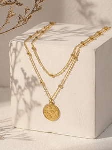 Détail du collier doré double rang avec pendentif œil protecteur et chaîne à perles