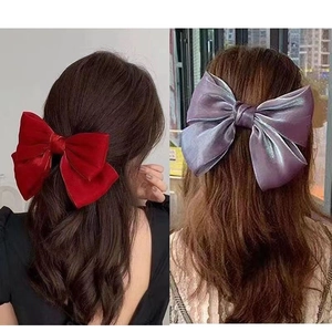 Detail view of large red velvet and iridescent purple satin bow hair clips for women