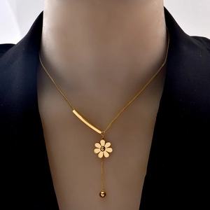 Detail shot of a golden flower pendant necklace with elegant tassels on a black suit