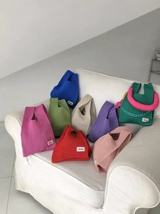Colorful knitted hollow tote bags stacked on a white sofa with vibrant mesh texture