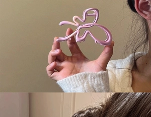 Close-up of a matte pink hollow butterfly hair claw clip with a detailed spring mechanism
