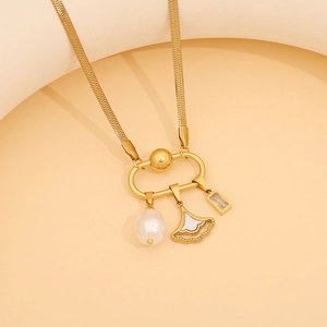 Detail of gold snake chain necklace with pearl, shell, and zircon pendants on beige prop