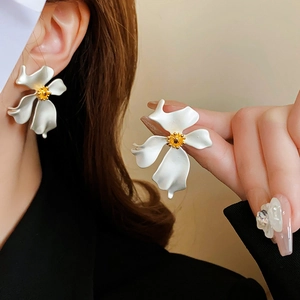 Close-up of vintage matte metal flower earrings with white petals and yellow centers
