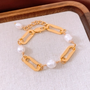 Detailed view of 18k gold plated chain bracelet with elegant white pearls on linen