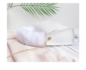 Close-up of elegant white square bag with plush faux fur handle and gold chain strap