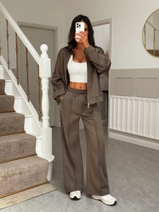 Detail of a brown two-piece leisure track suit with zip-up jacket and wide-leg pants