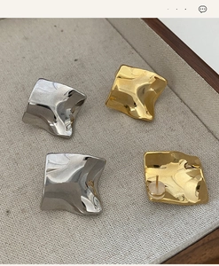Detailed view of irregular wave earrings in gold and silver finish with silicone backs