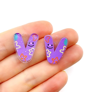 Detail of purple acrylic letter V pendant with colorful smiley and flower patterns