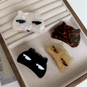 Detailed view of cat-shaped acetate hair claws in four colors on a velvet display tray