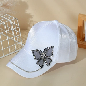 Detail of white satin baseball cap with rhinestone butterfly and decorative crystal chain