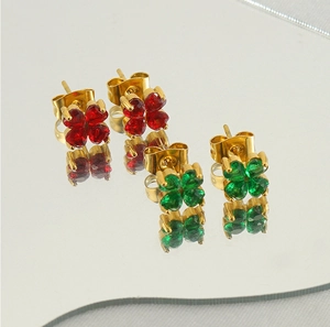 Détail de boucles d'oreilles trèfle avec zircons rouges et verts sur un miroir