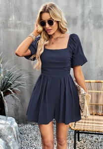 Detail of navy blue square neck romper with puff sleeves and pleated shorts detail