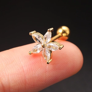 Macro shot of gold flower cartilage stud featuring five sparkling zircon stones on finger
