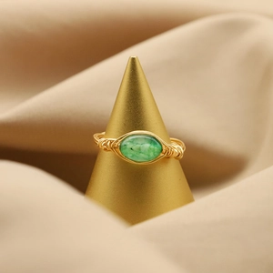 Handcrafted gold wire wrapped ring featuring an oval green jade gemstone on a display stand